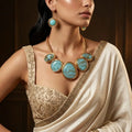 Turquoise blue resin statement necklace with gold-tone frames and ivory saree – festive jewellery for women – Oneofé